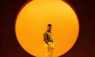 A man in an orange circle staring into space