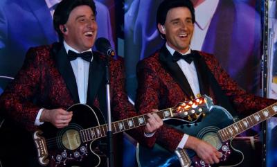 Two men in wigs and suits with guitars