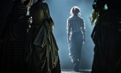 The back of a woman surrounded by other women in period costume